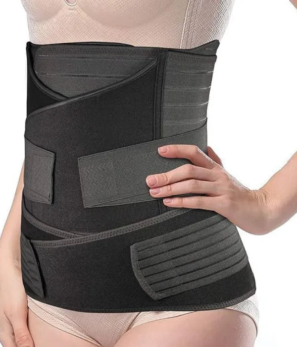 Black 3-in-1 postpartum support belt worn by a woman, left-side view, with hands adjusting the waist and pelvis bands.